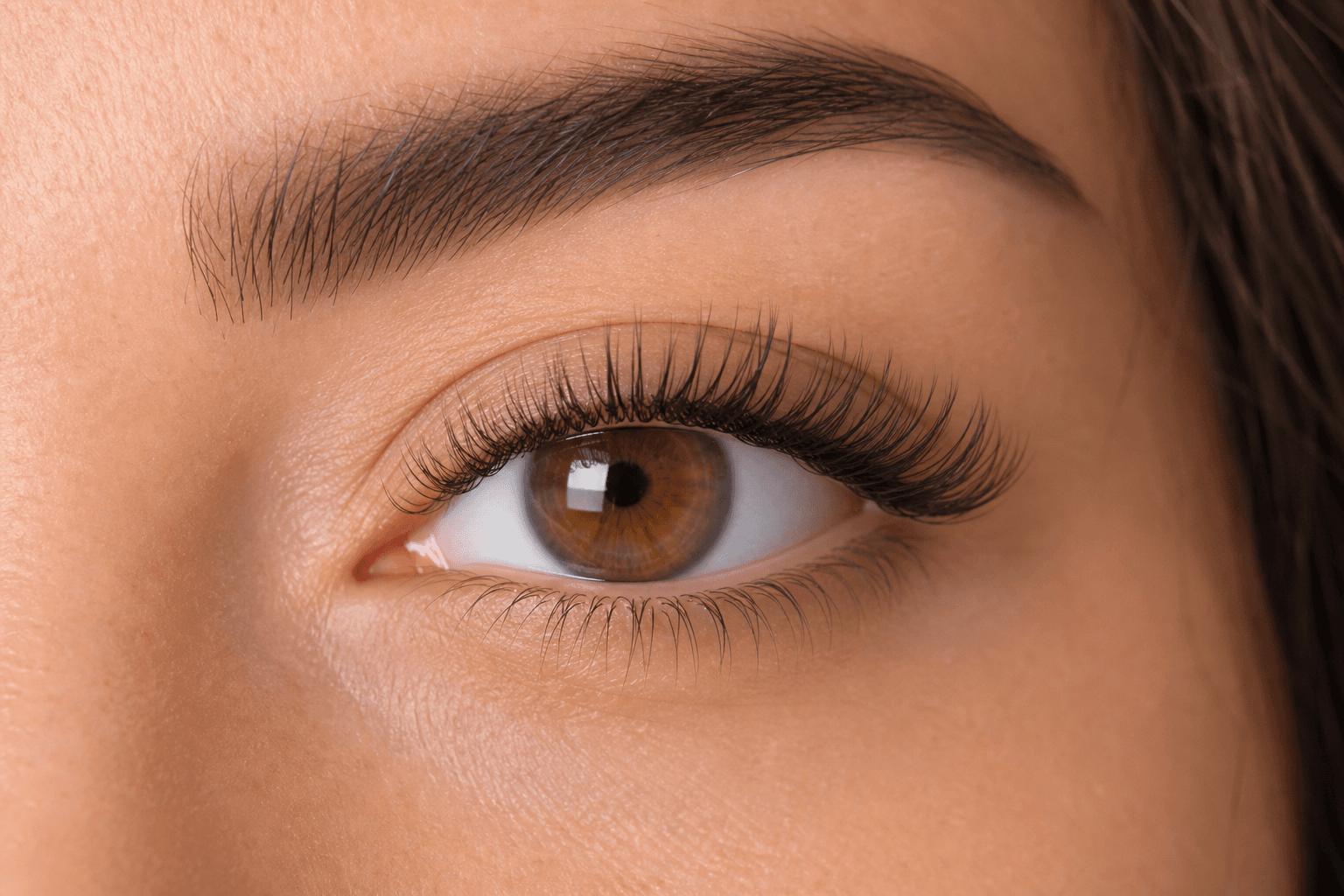 Illustrative close-up of a brown eye with long, defined upper lashes